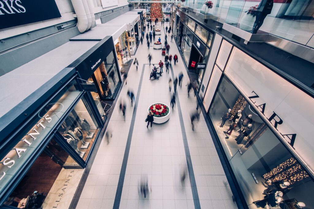 A vibrant scene capturing a busy shopping mall with modern stores and diverse shoppers on the move.
