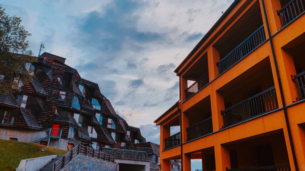 Contrast between modern architecture and unique shingle facade under a vibrant sky.